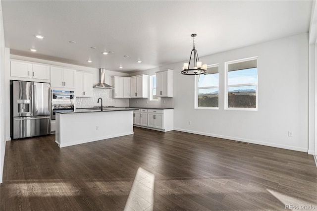 kitchen with white cabinetry, appliances with stainless steel finishes, pendant lighting, wall chimney range hood, and backsplash