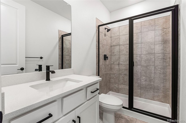 bathroom with tile patterned floors, vanity, toilet, and a shower with shower door