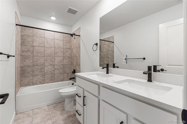 full bathroom with tiled shower / bath, vanity, and toilet