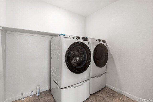 laundry room with light tile patterned flooring and washing machine and clothes dryer