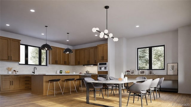 kitchen with pendant lighting, a breakfast bar area, light hardwood / wood-style flooring, tasteful backsplash, and oven