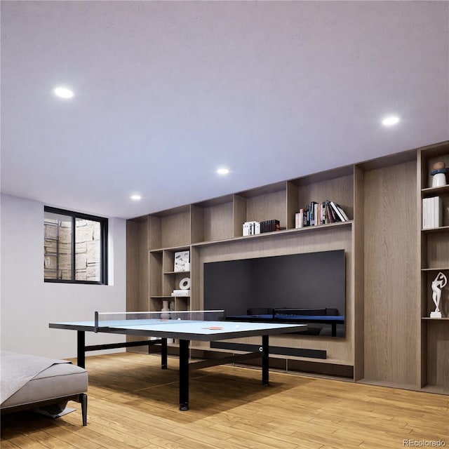 playroom with built in shelves and light hardwood / wood-style flooring