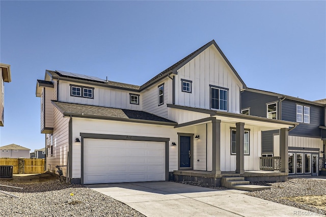 view of front facade featuring a garage, central AC, solar panels, and a porch