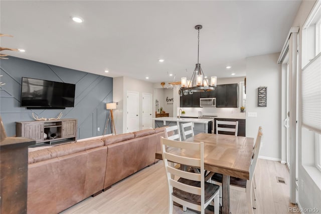 dining room with a notable chandelier, light hardwood / wood-style flooring, and a wealth of natural light