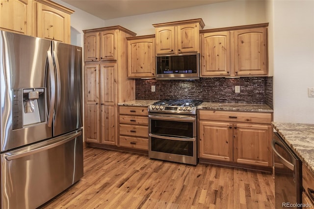 1715 Wales Dr, Berthoud, CO 80513 - kitchen with appliances with stainless steel finishes, light stone counters, light wood-type flooring, and tasteful backsplash