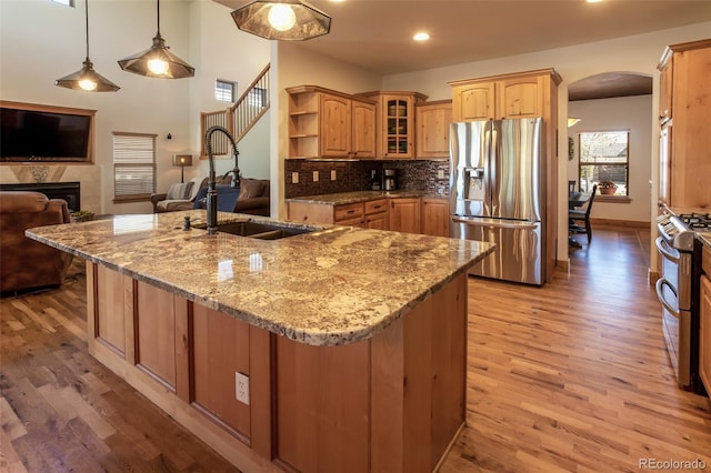 1715 Wales Dr, Berthoud, CO 80513 - kitchen with appliances with stainless steel finishes, arched walkways, light wood finished floors, light stone countertops, and recessed lighting