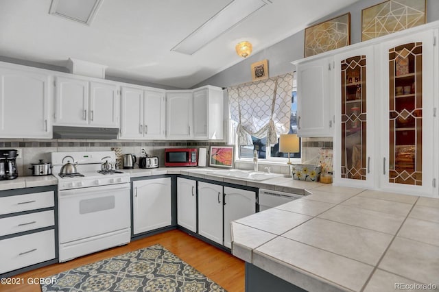 kitchen with white gas range, a sink, under cabinet range hood, and tile counters