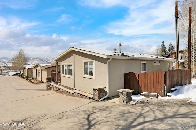 rear view of house featuring cooling unit, fence, and stucco siding