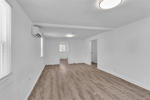 spare room with an AC wall unit and light hardwood / wood-style flooring