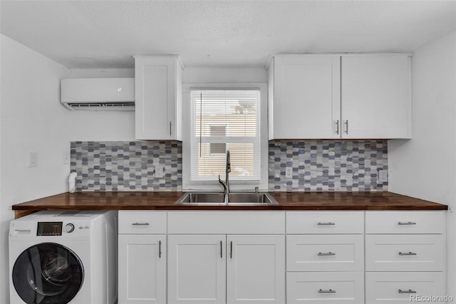 kitchen with white cabinetry, sink, backsplash, washer / dryer, and an AC wall unit