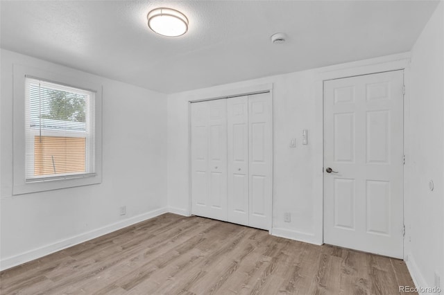 unfurnished bedroom with a textured ceiling, a closet, and light wood-type flooring