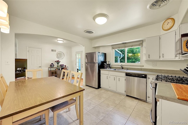 3313 S Dexter St, Denver, CO 80222 - kitchen with appliances with stainless steel finishes, arched walkways, light tile patterned floors, white cabinets, and light countertops