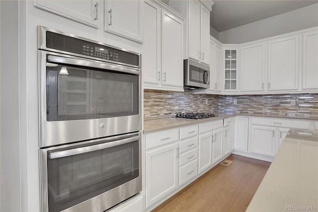 kitchen featuring stainless steel appliances, tasteful backsplash, light hardwood / wood-style flooring, and white cabinetry