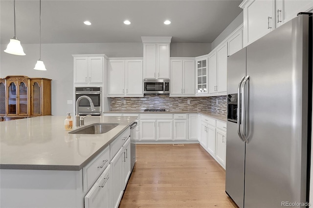 kitchen with light wood-type flooring, pendant lighting, white cabinetry, and stainless steel appliances