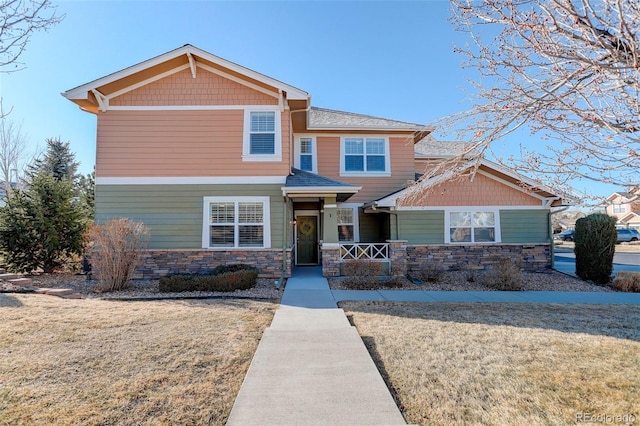 craftsman inspired home featuring stone siding, a front lawn, and covered porch