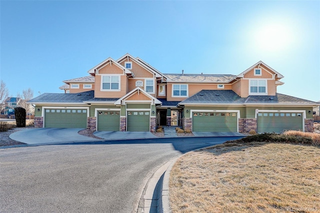 view of front facade featuring a garage, stone siding, and aphalt driveway