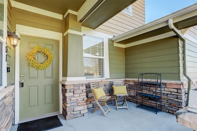 view of exterior entry with stone siding and a porch