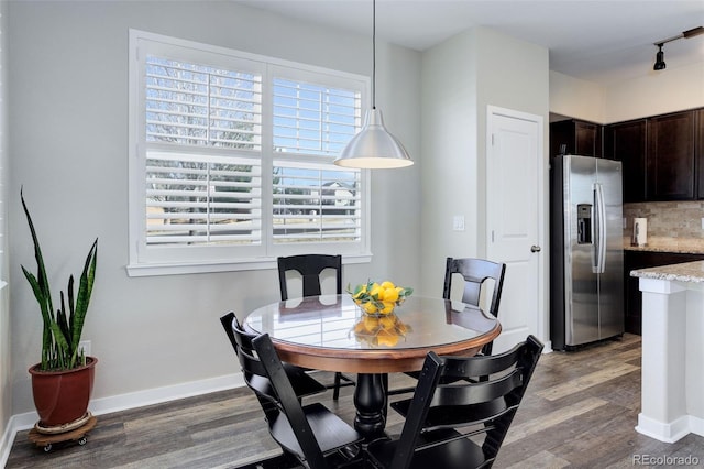 dining space featuring track lighting, wood finished floors, and baseboards