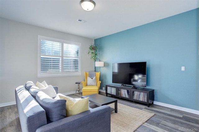 living room featuring visible vents, baseboards, and wood finished floors