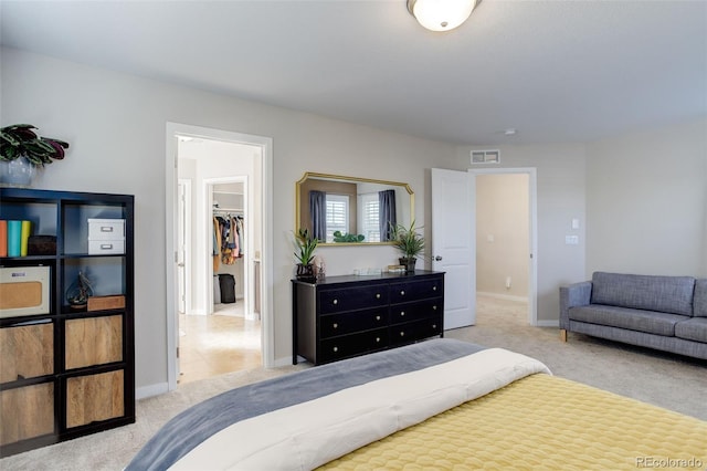 carpeted bedroom with a walk in closet, visible vents, and baseboards