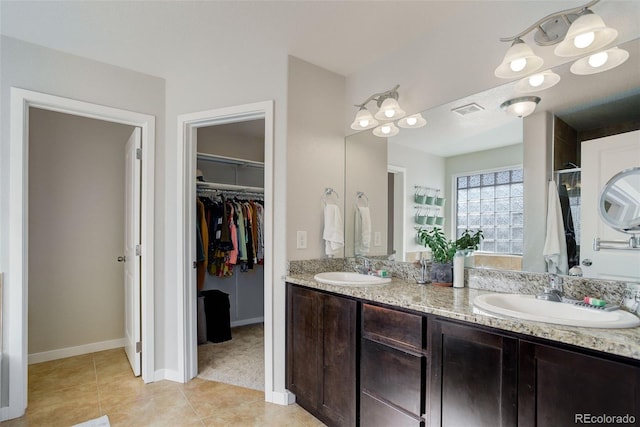 bathroom featuring tile patterned flooring, a spacious closet, visible vents, and a sink