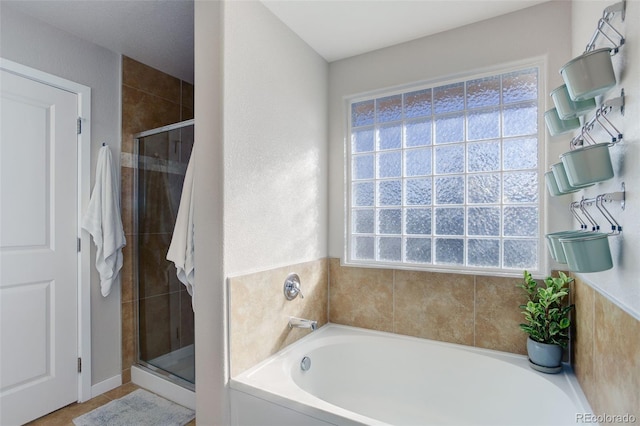 full bath with a stall shower, plenty of natural light, and a bath