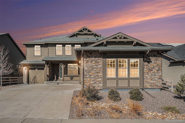 view of front of property with a garage, stone siding, driveway, and fence