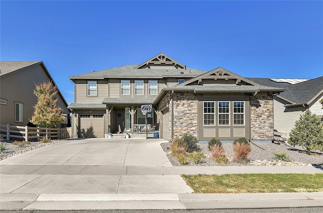 view of front facade with driveway, stone siding, a garage, and fence