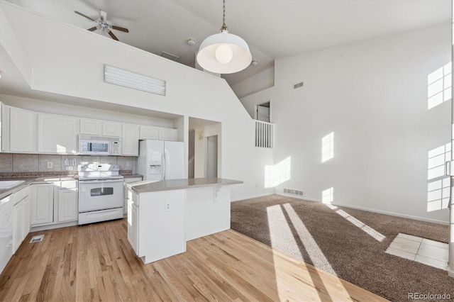 kitchen with white cabinetry, decorative light fixtures, high vaulted ceiling, a kitchen island, and white appliances