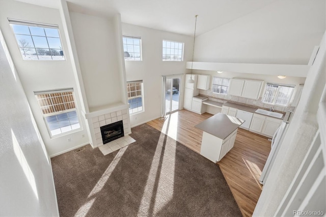 living room featuring sink, a towering ceiling, a fireplace, and light hardwood / wood-style floors