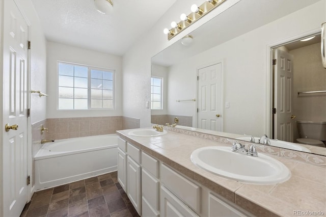 bathroom featuring vanity, a bath, a textured ceiling, and toilet