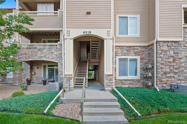 property entrance with stone siding and central AC