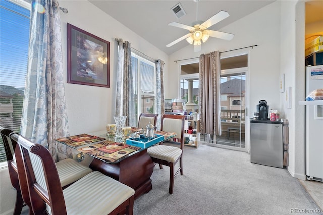 carpeted dining area with visible vents, a ceiling fan, and vaulted ceiling
