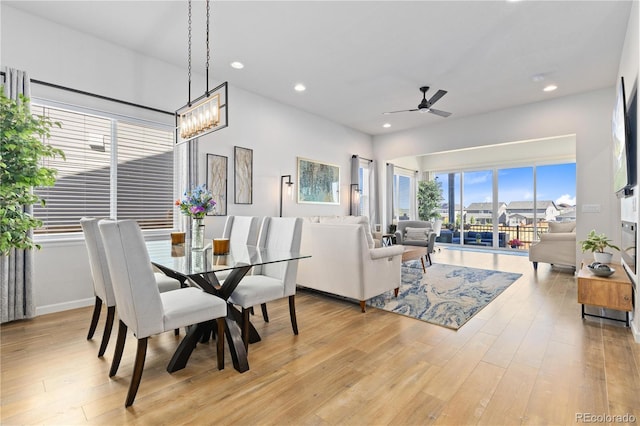 dining space with ceiling fan with notable chandelier and light hardwood / wood-style flooring