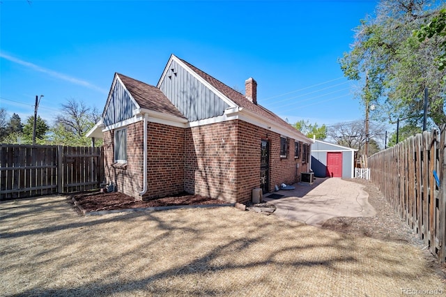 7275 E 8th Ave, Denver, CO 80220 - view of property exterior featuring brick siding, a chimney, board and batten siding, a fenced backyard, and a patio area