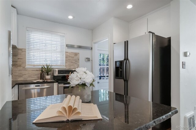 7275 E 8th Ave, Denver, CO 80220 - kitchen featuring appliances with stainless steel finishes, tasteful backsplash, dark stone counters, white cabinets, and recessed lighting