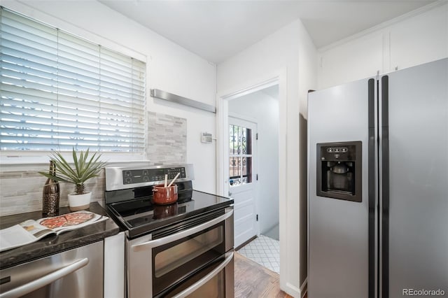7275 E 8th Ave, Denver, CO 80220 - kitchen with stainless steel appliances, wood finished floors, tasteful backsplash, white cabinets, and dark countertops