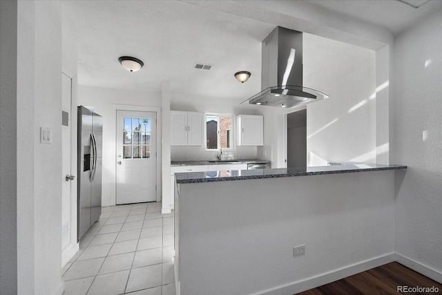 kitchen featuring white cabinets, island range hood, kitchen peninsula, and appliances with stainless steel finishes