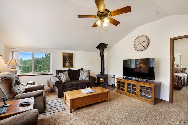 living room with a wood stove, lofted ceiling, carpet floors, and ceiling fan