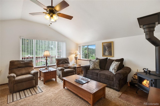 carpeted living room featuring a wood stove, ceiling fan, and vaulted ceiling