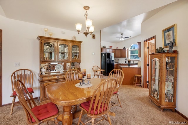 carpeted dining area with ceiling fan with notable chandelier