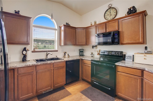 kitchen featuring black appliances, sink, light stone countertops, vaulted ceiling, and light hardwood / wood-style floors