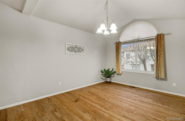 spare room with vaulted ceiling, a notable chandelier, and light hardwood / wood-style floors