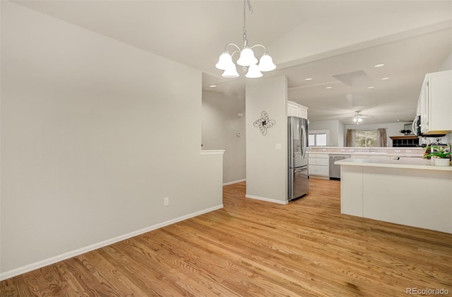 kitchen with stainless steel appliances, light hardwood / wood-style floors, white cabinetry, kitchen peninsula, and hanging light fixtures