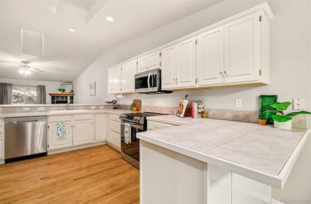 kitchen with stainless steel appliances, light wood-type flooring, tile countertops, kitchen peninsula, and ceiling fan