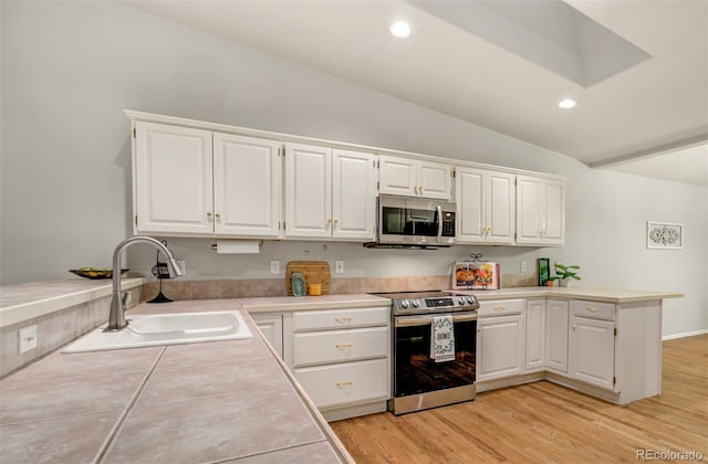 kitchen featuring white cabinetry, sink, appliances with stainless steel finishes, light hardwood / wood-style flooring, and lofted ceiling