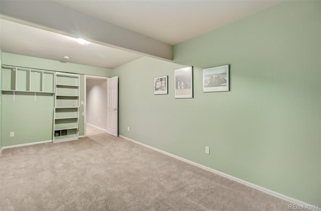 unfurnished bedroom featuring a closet, beamed ceiling, and light colored carpet