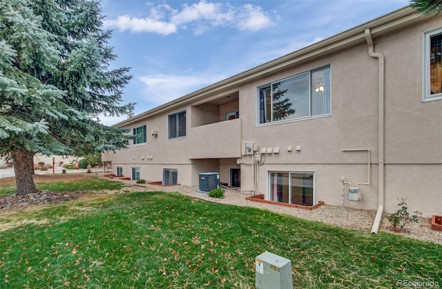 back of house with a lawn and central AC