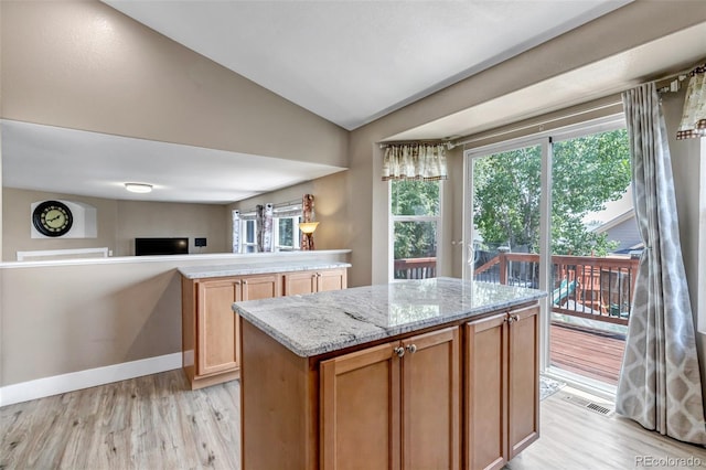 16352 E 104th Way, Commerce City, CO 80022 - kitchen featuring light wood finished floors, vaulted ceiling, light stone countertops, open floor plan, and a center island