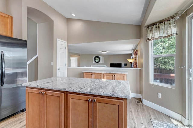 16352 E 104th Way, Commerce City, CO 80022 - kitchen featuring stainless steel fridge, light wood-type flooring, light stone counters, vaulted ceiling, and open floor plan